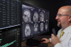 A radiologist reading brain scan images on 2 monitors