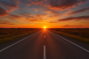 A sun set on the horizon over a road